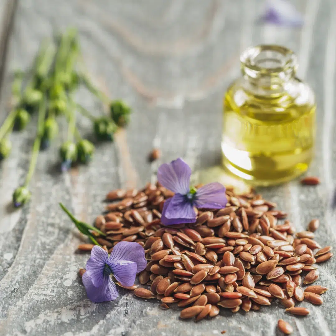 Flaxseeds with flax oil and flowers providing fiber and lignans to bind excess estrogen and aid hormonal balance.