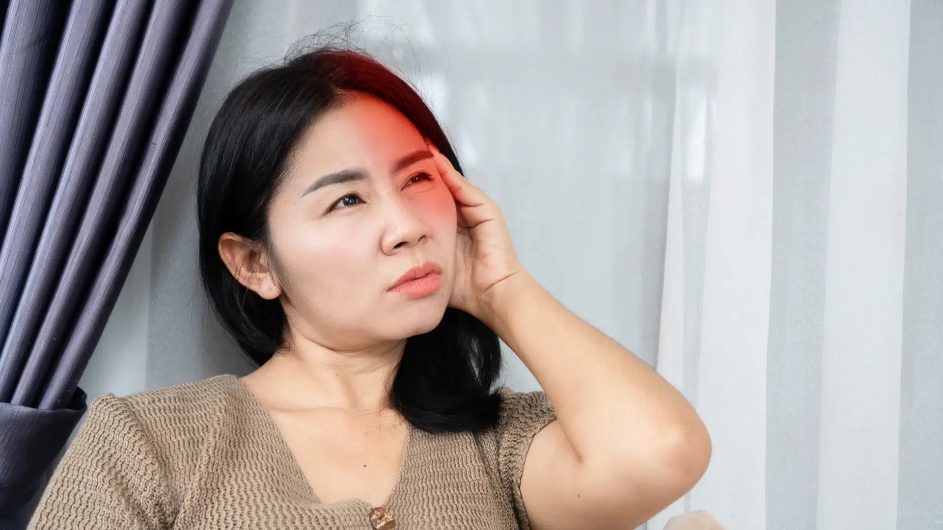 Woman experiencing a severe migraine, with pain visualized as a red glow at its source.